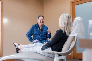 Dentist talking with patient in chair about routine dental cleanings.
