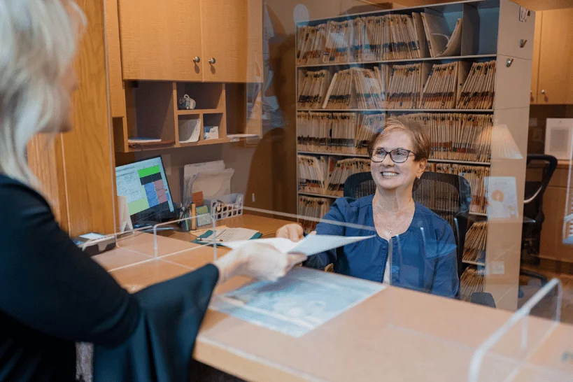Dental staff member smiling while receiving patient form