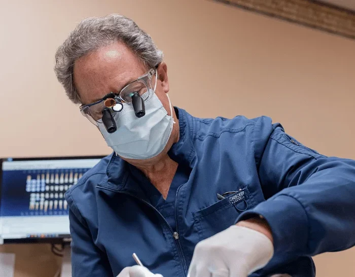 Male dentist wearing loupes performing dental treatment on patient