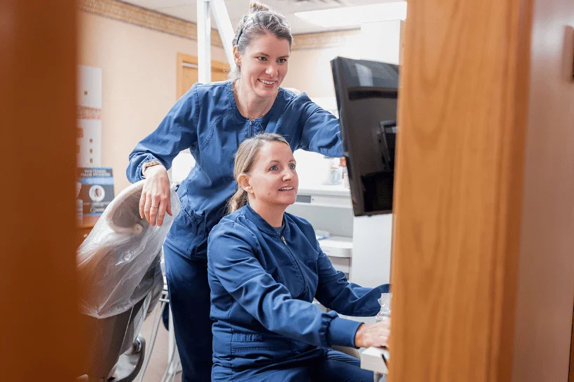 Two dental assistants checking patient details on computer