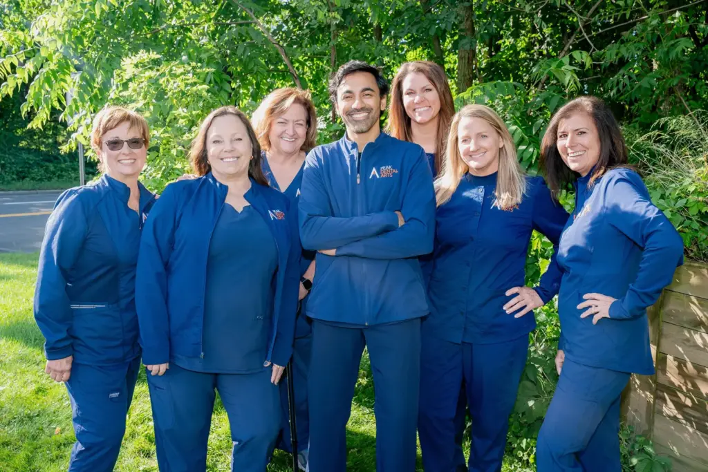 Peak Dental Arts team outdoors for group team photo in front of pond with trees in the background